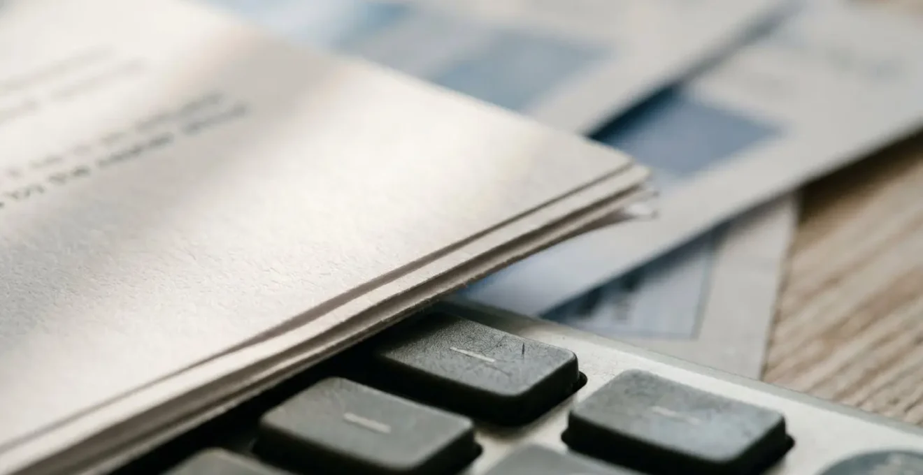 Bureau avec documents d'assurance éparpillés et calculatrice montrant des économies